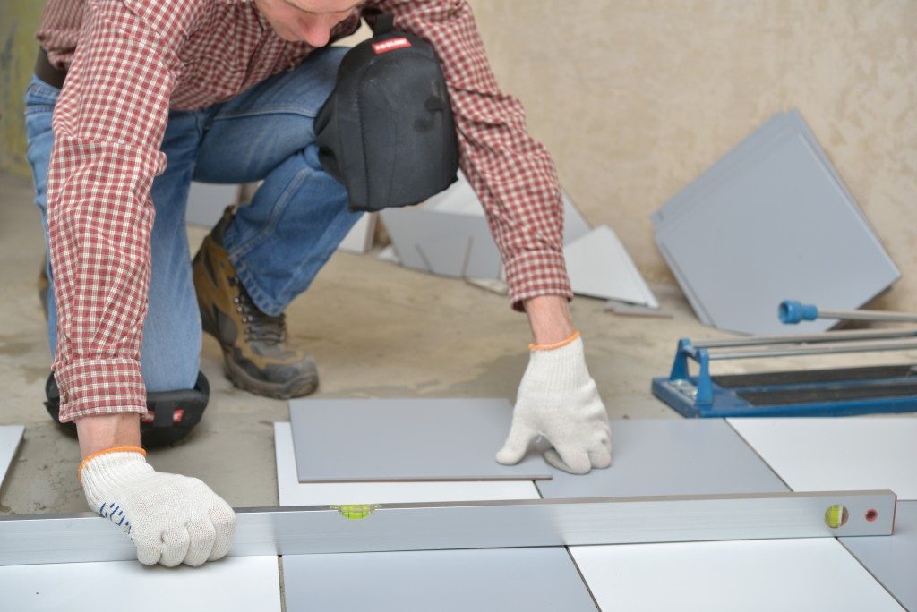 worker measuring distance between tiles