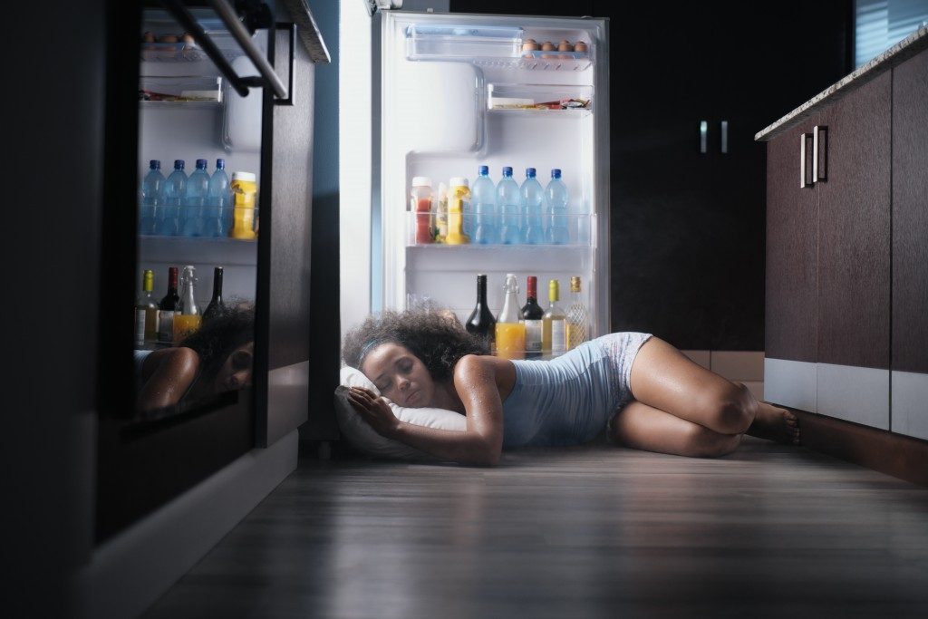 woman sleeping near an open fridge