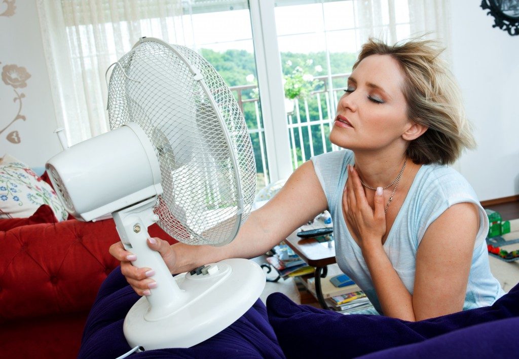 woman cooling herself with fan