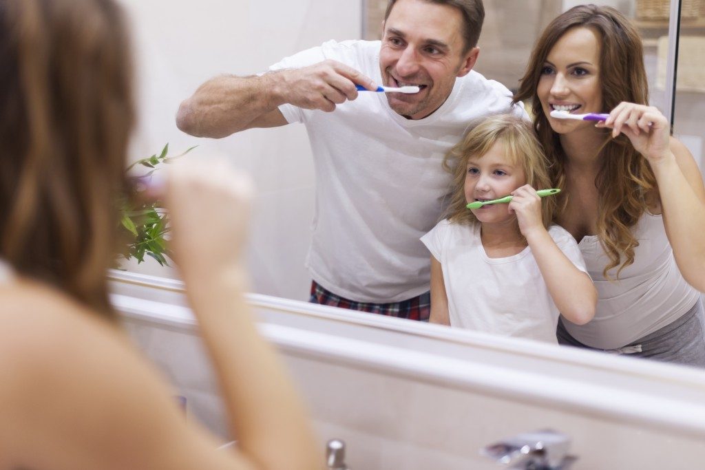 mom and dan brushing teeth with daughter