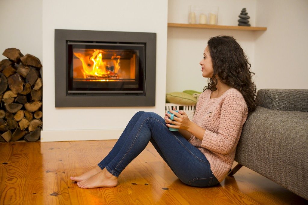 Woman sitting in front of her modern fireplace