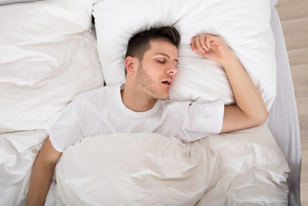 man sleeping soundly under comforter