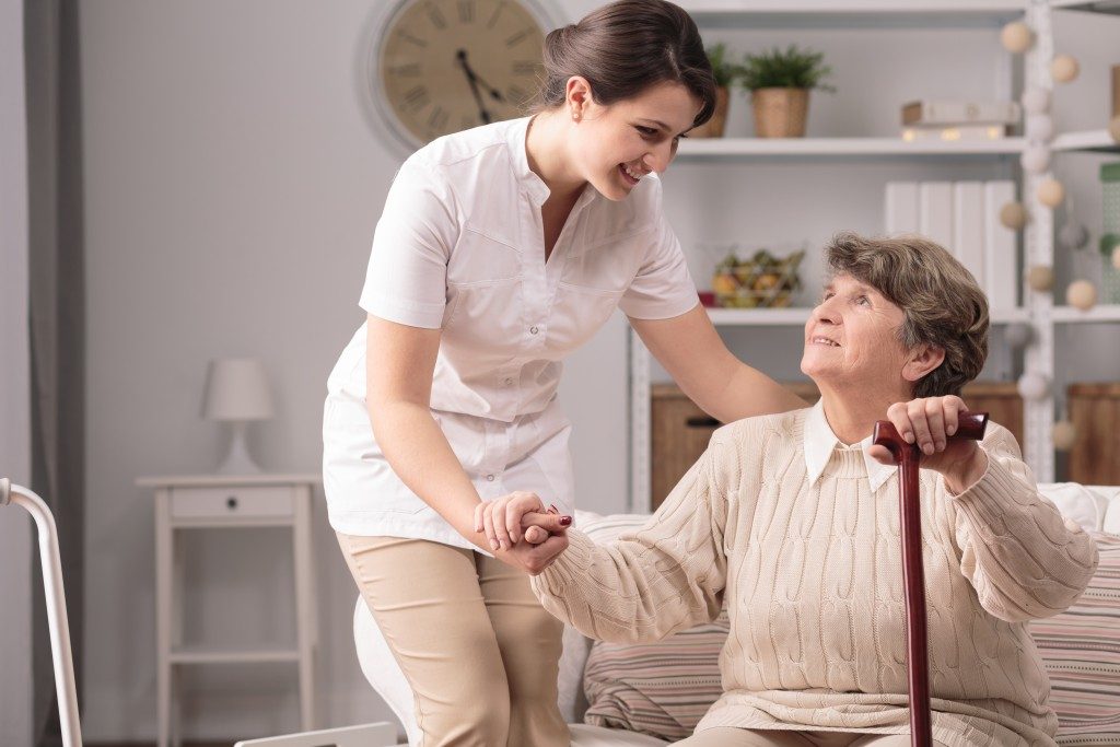 caregiver assisting an old woman to stand up