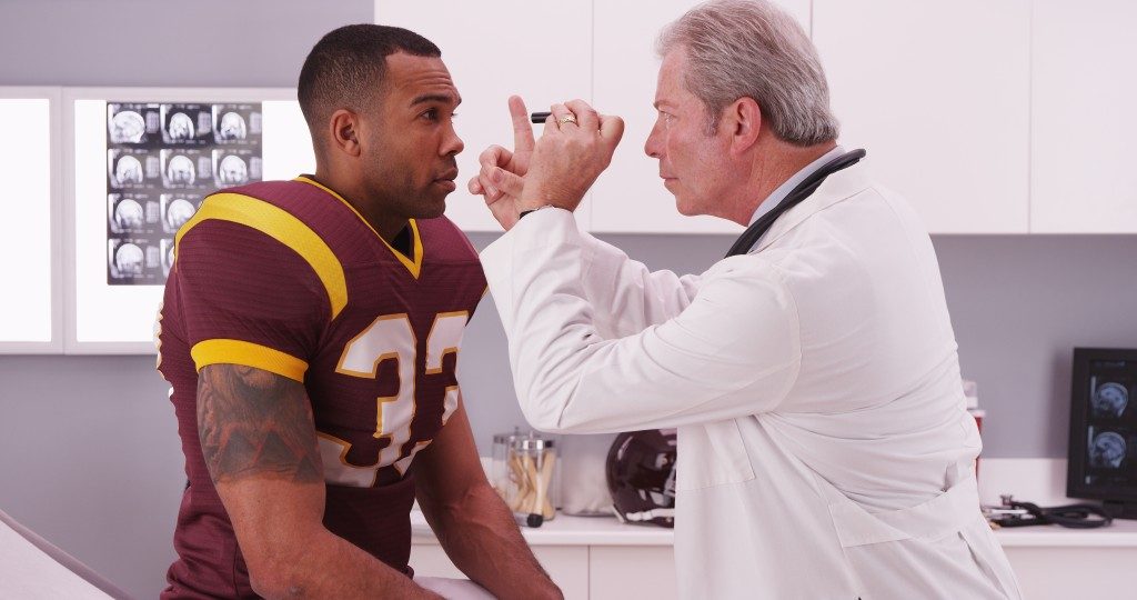 football player having senior doctor review his concussion injury