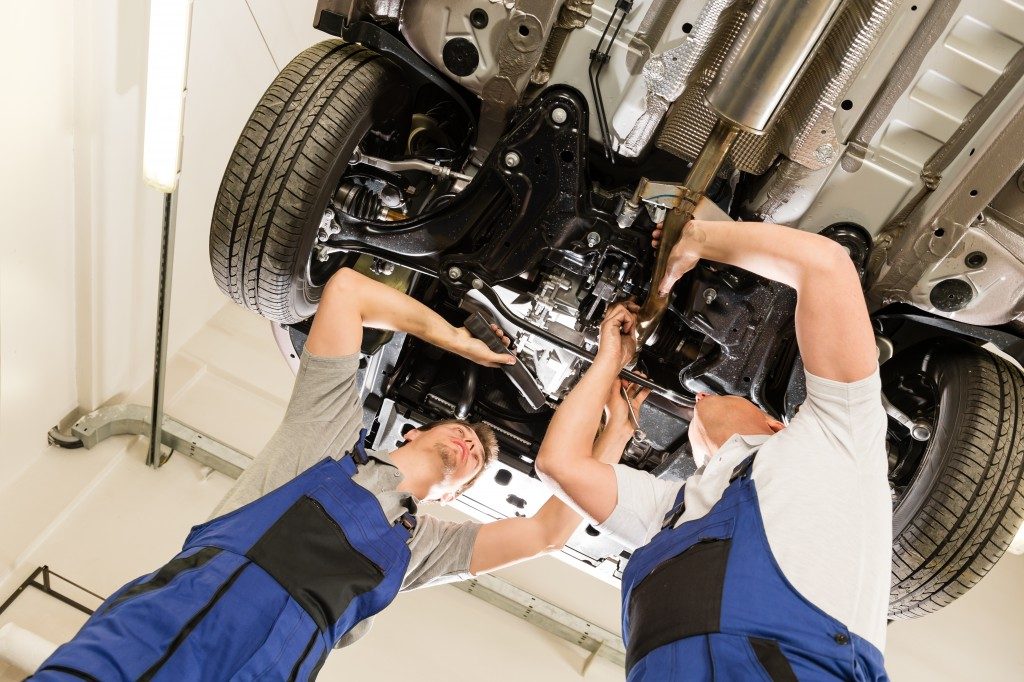 two mechanics checking the engine of a car