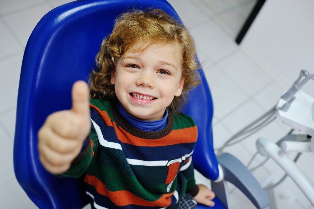 smiling kid sitting on the dental chair