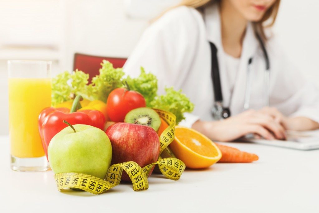 Doctor with fruits and veggies on the table, recommending diet
