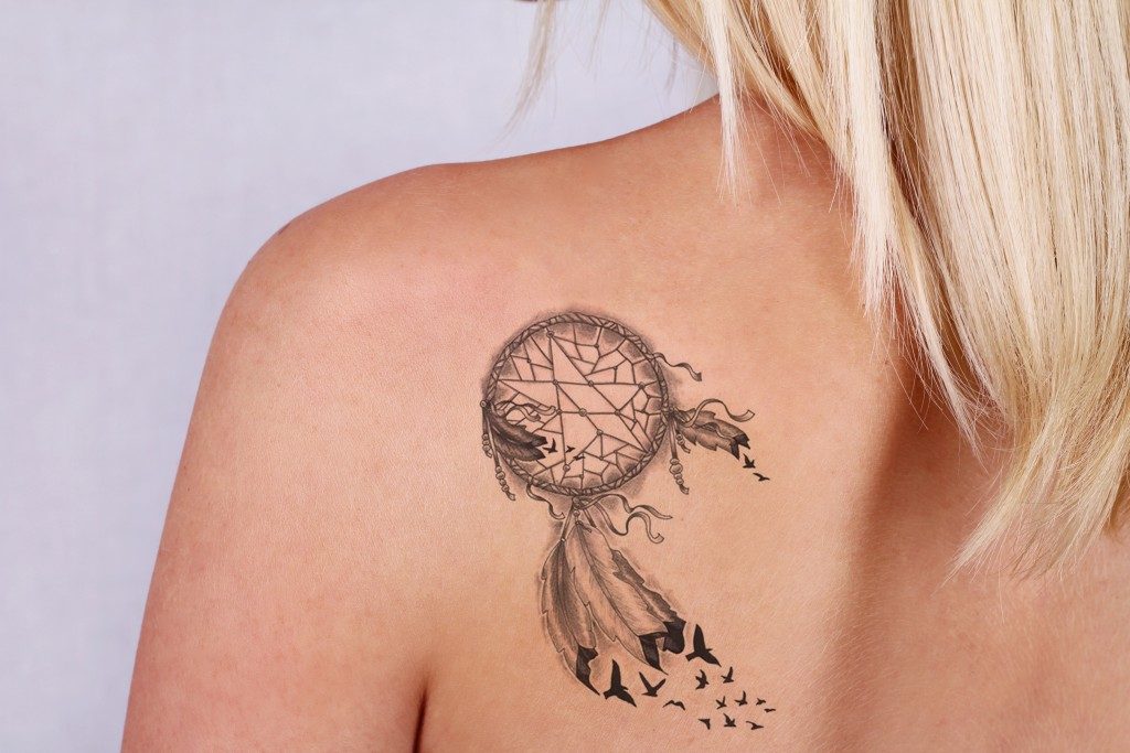 Laser tattoo removal concept. Beautiful young woman with tattoo on her back