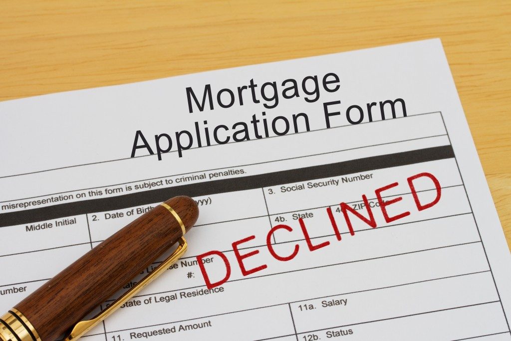 Mortgage Application Form with declined stamp and a pen on a wooden desk