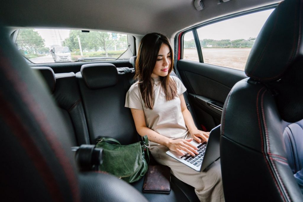 woman working on laptop inside a car