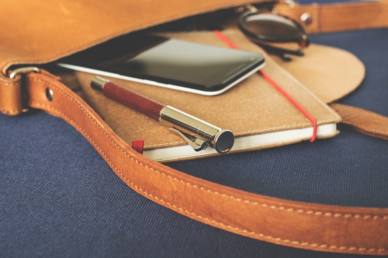 leather bag with sunglasses, phone, notebook and a pen inside.