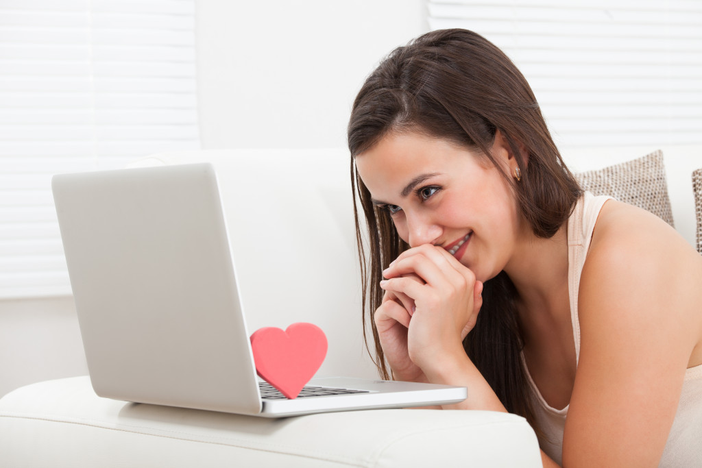 A smiling woman facing her laptop