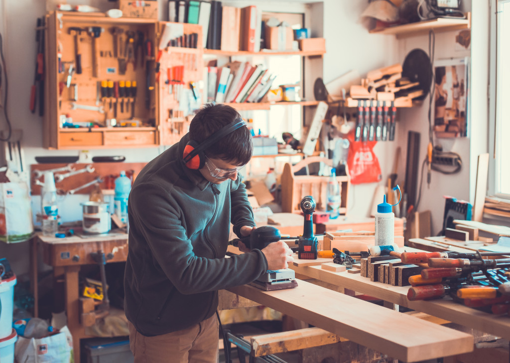 man cutting a block of wood inside his workshop