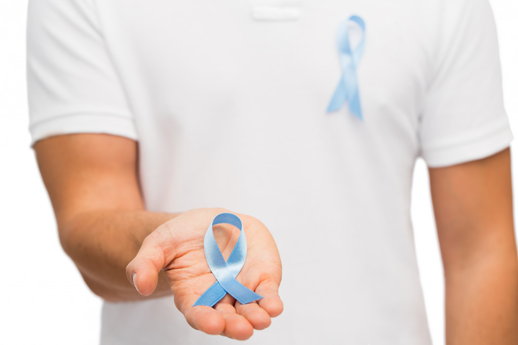 man holding blue ribbon on hand concept of prostate cancer awareness