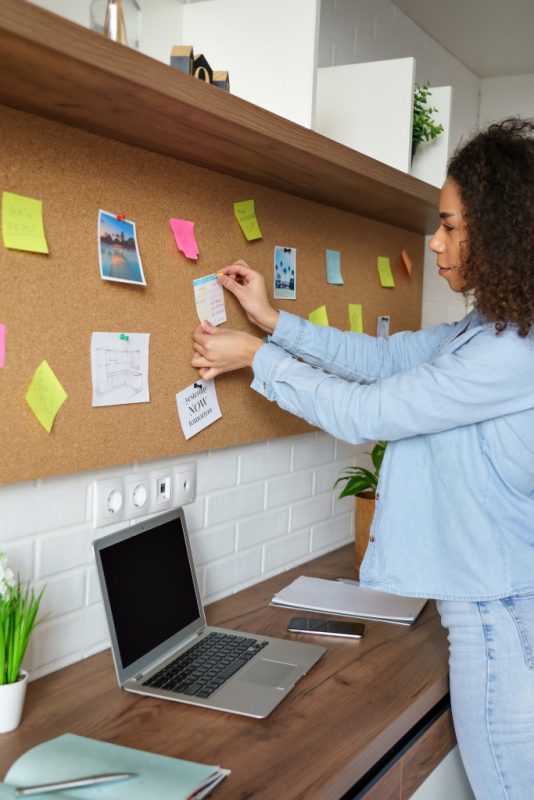 A woman pinning notes on a cork board