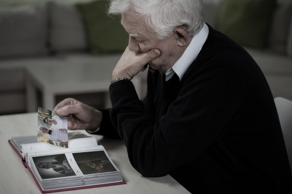 lonely senior widower looking at old photos
