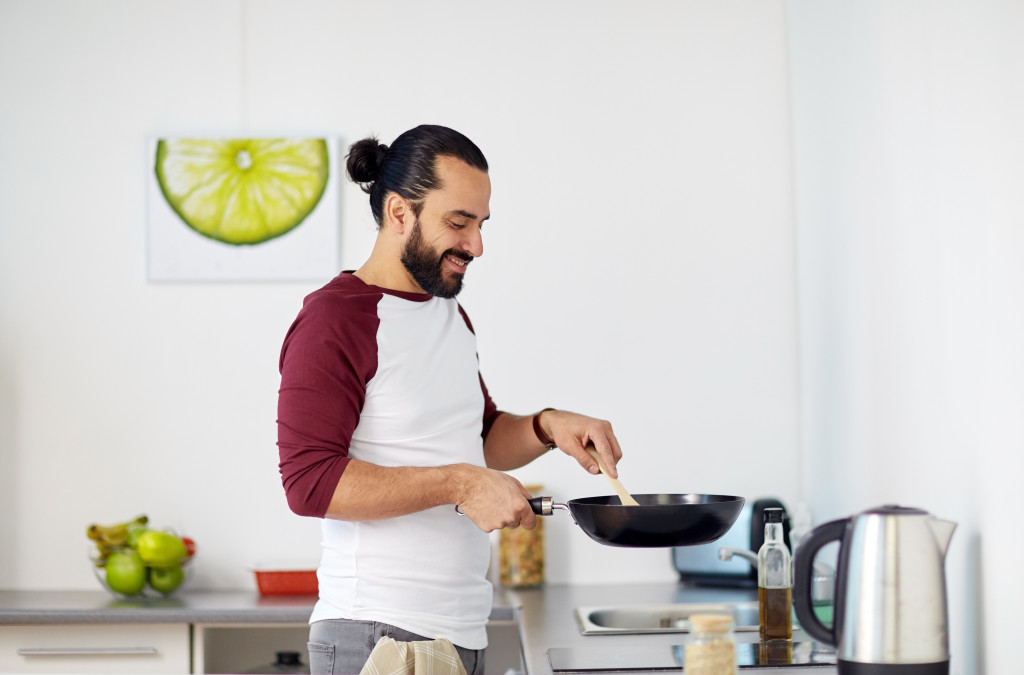 man holding a pan in the kitchen cooking