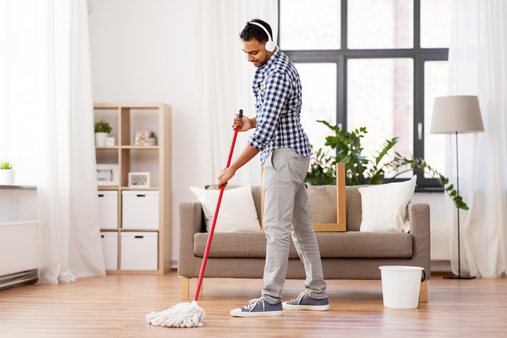 solo man cleaning his living room with a mop
