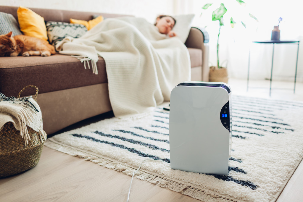 an air purifier open in the living room while woman sleeps on the couch