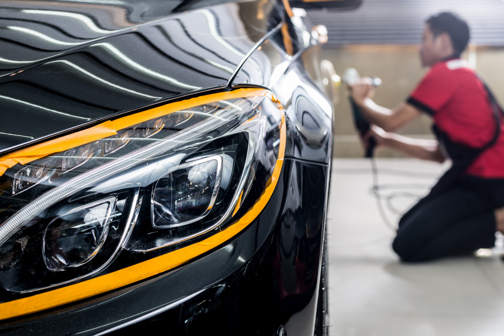 man buffing the side of a shiny black car