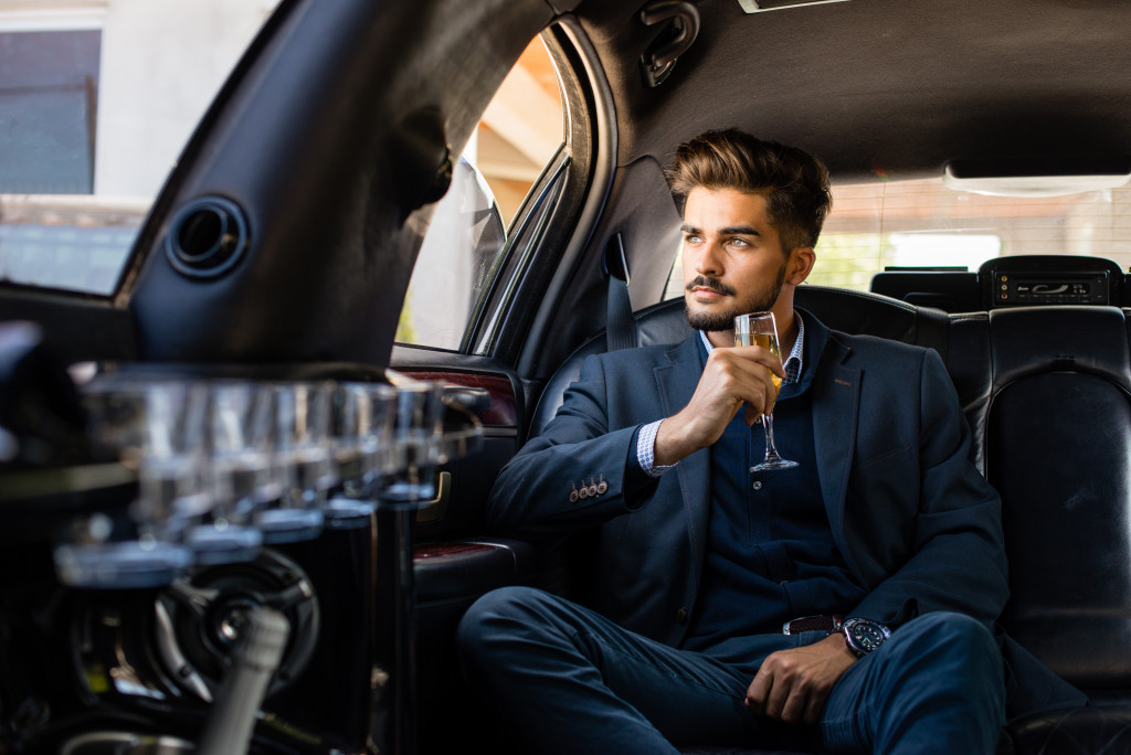 man inside his car drinking wine